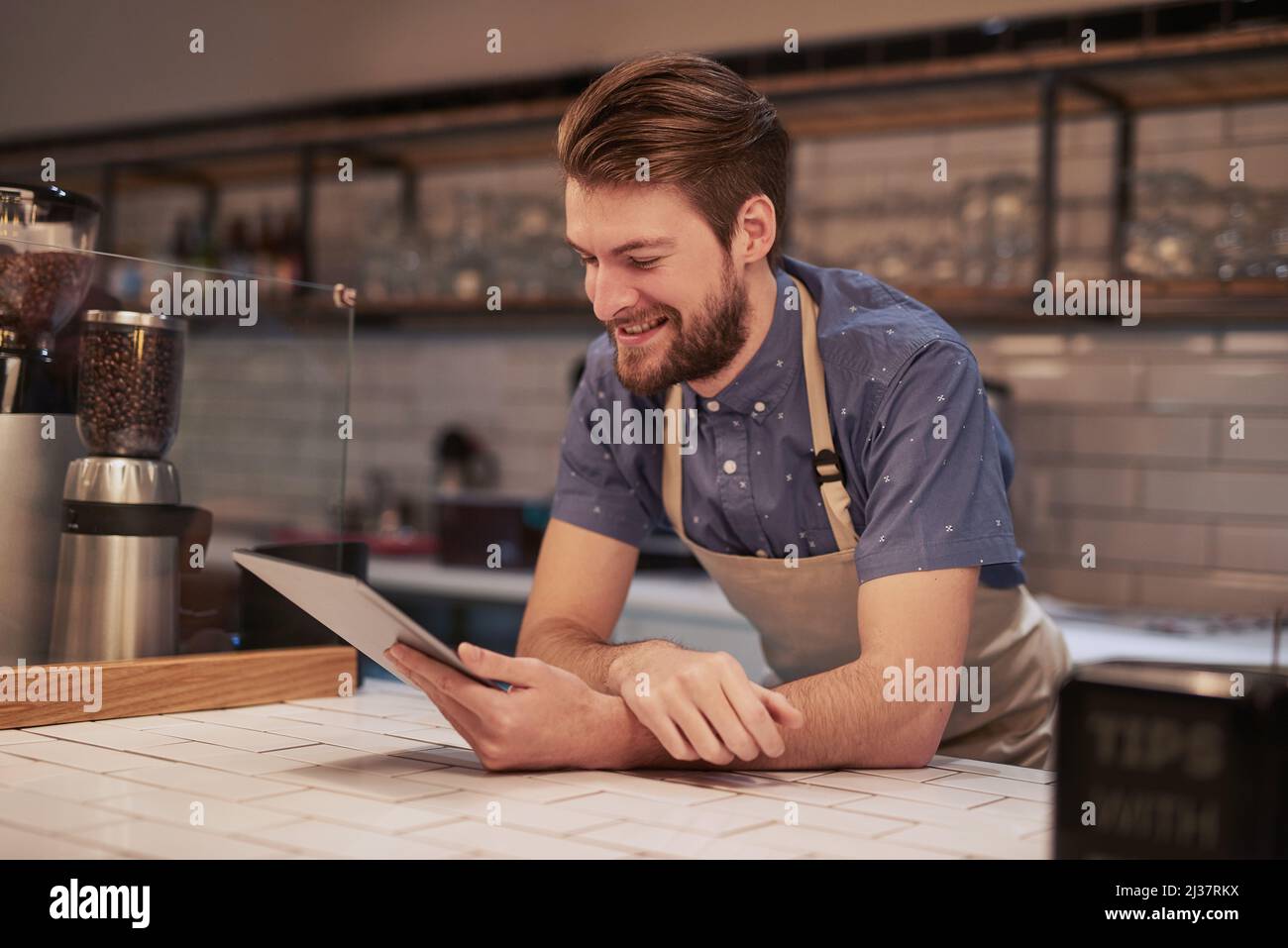 Creazione di pubblicità online poco costose per il pubblico locale di destinazione. Scatto di un giovane che usa un tablet digitale mentre lavora in un bar. Foto Stock