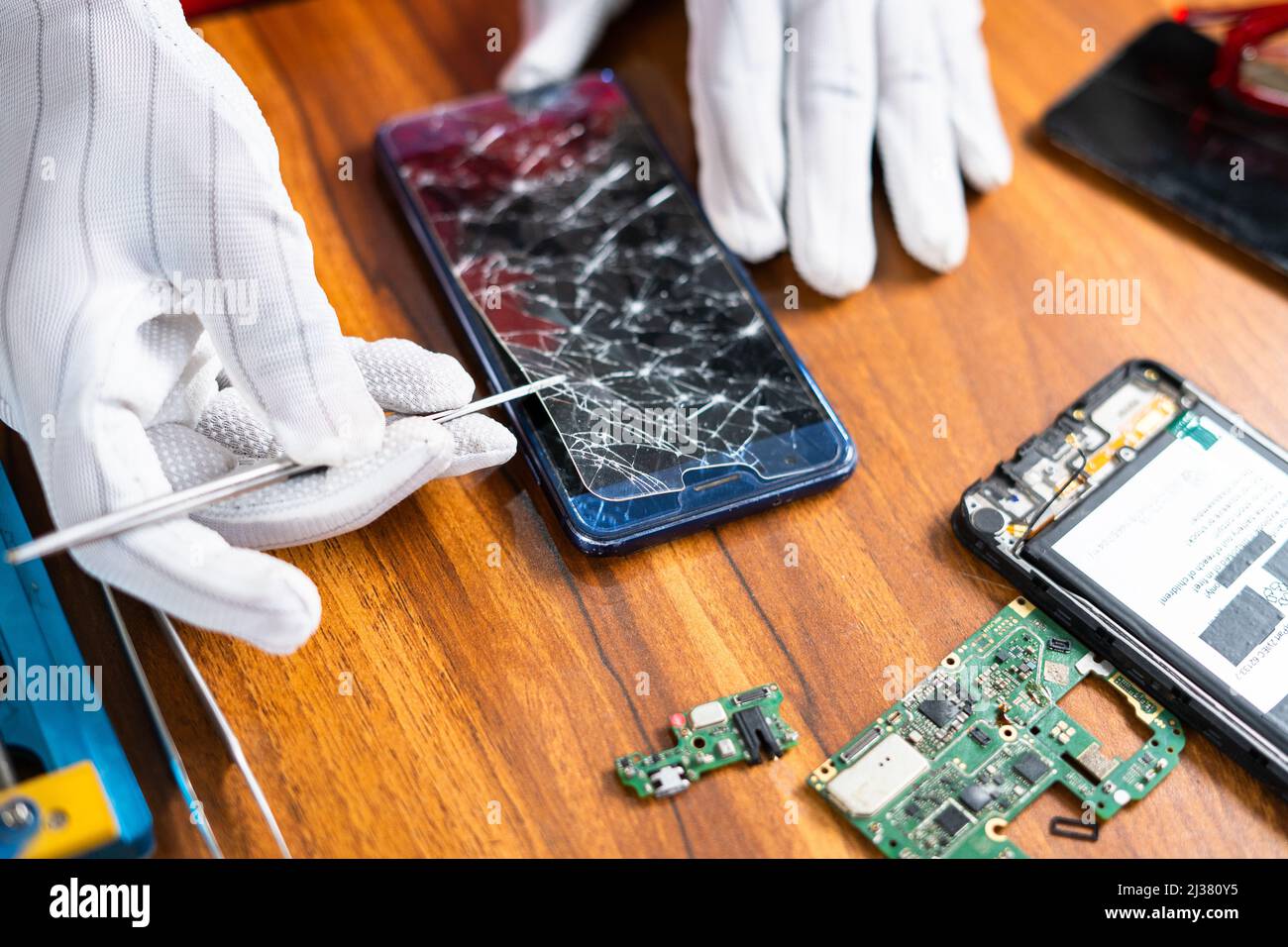 primo piano del tecnico che rimuove o ripara il display rotto del telefono cellulare in officina - concetto di lavoratore qualificato, professionale e piccolo Foto Stock