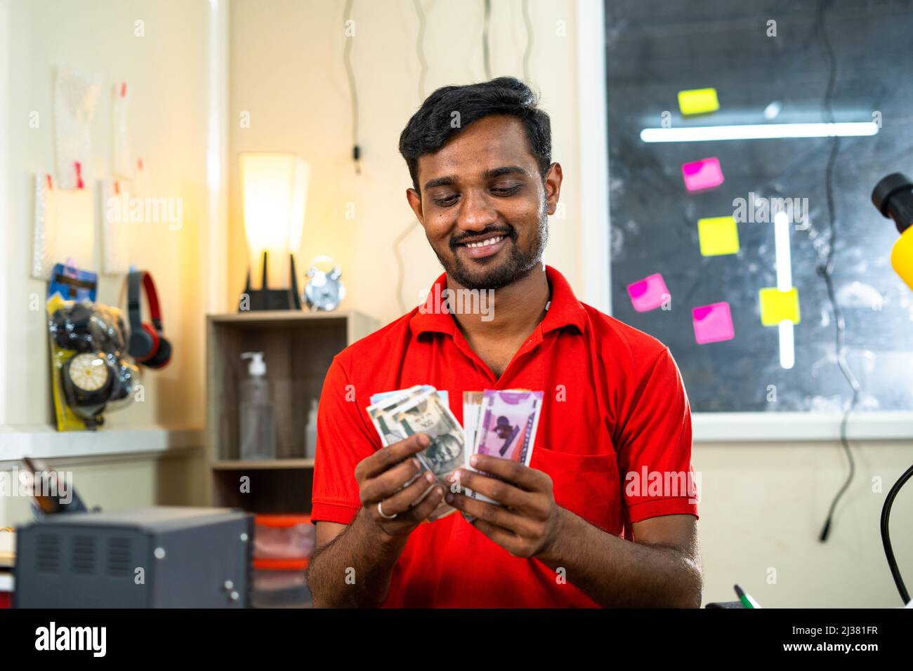 Tecnico mobile felice contare denaro presso il negozio di riparazione - concetto di profitto aziendale, guadagni e business di successo. Foto Stock