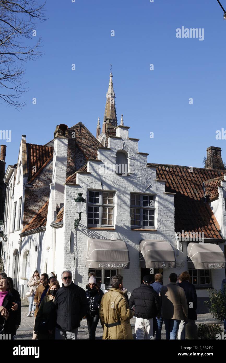 Tipica casa di Bruges, tetto a gradini, cioccolato in vendita e guglia chiesa Foto Stock