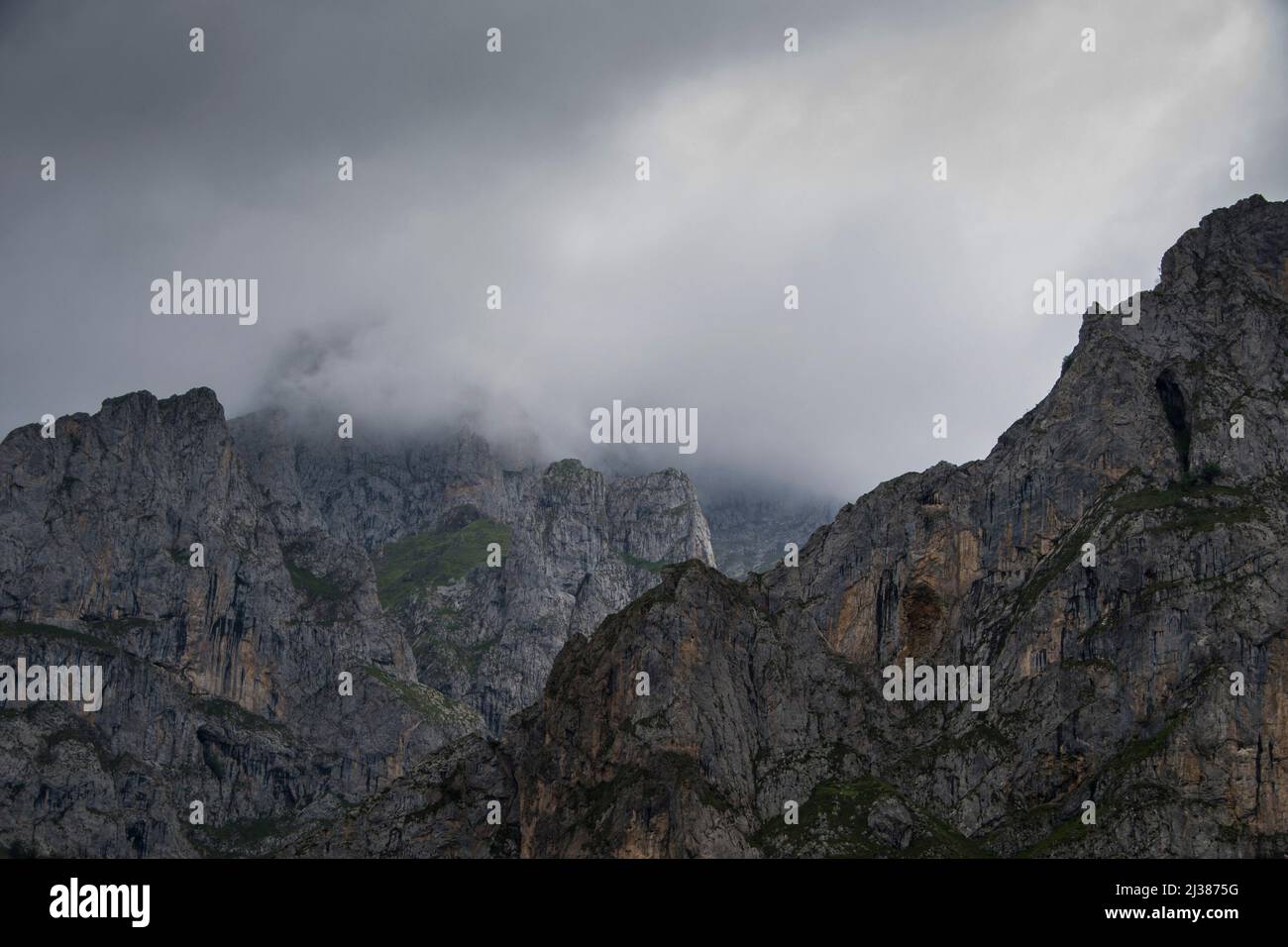 Imponenti e maestose cime calcaree acuminate si erigono alte tra la nebbia e il sole che respira le nuvole Foto Stock