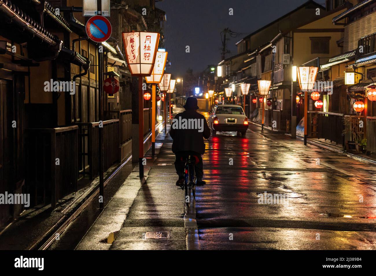 Uomo in bicicletta nel quartiere storico di Kyoto di notte Foto Stock