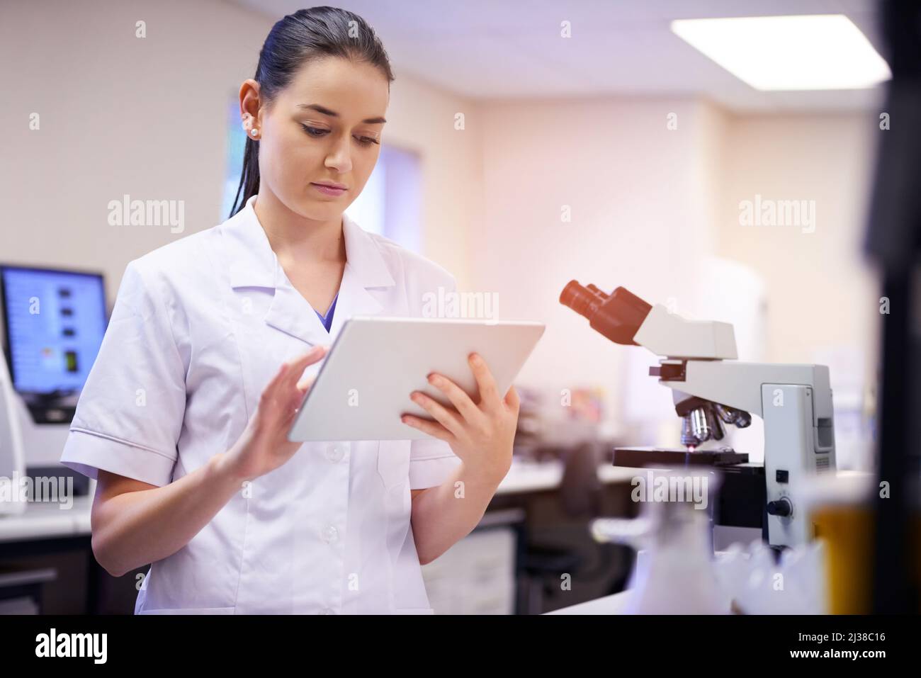 Analisi dei dati scientifici su un tablet digitale. Foto di un giovane scienziato che utilizza un tablet digitale mentre lavora in laboratorio. Foto Stock