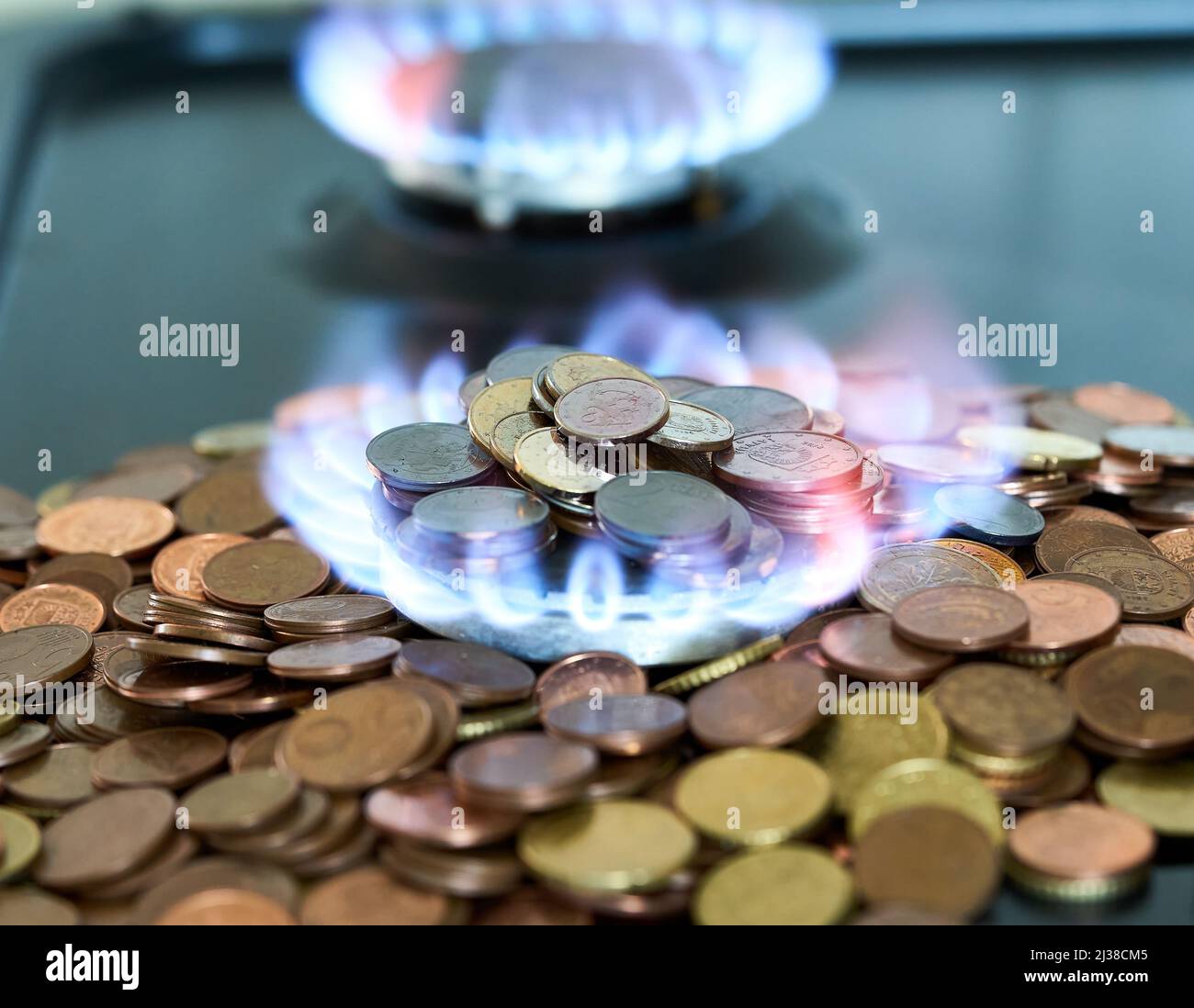 Monete metalliche in euro che bruciano nella stufa a gas Foto Stock