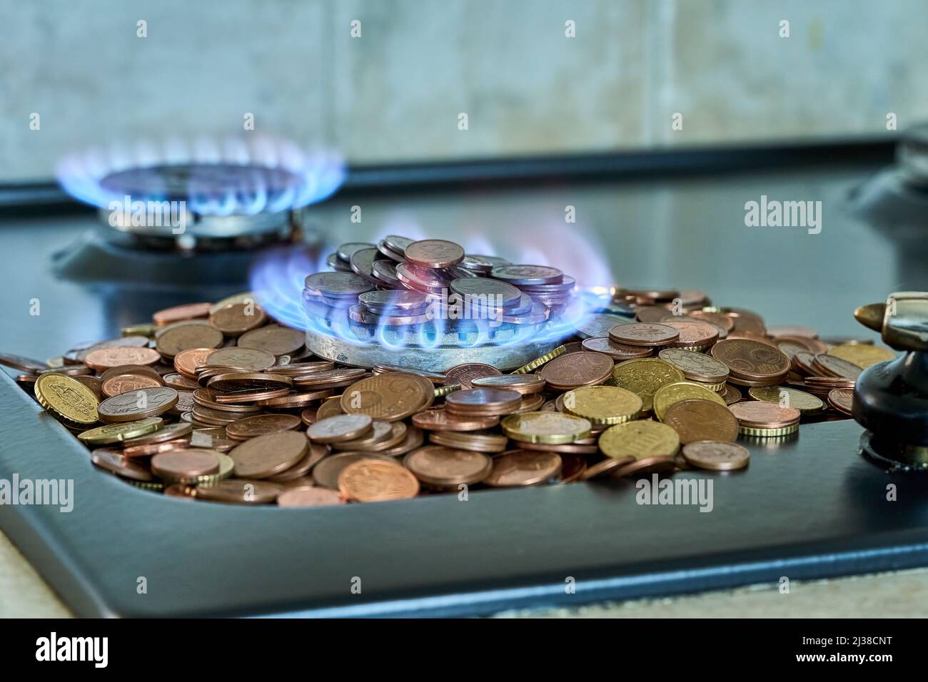 Monete metalliche in euro che bruciano nella stufa a gas Foto Stock