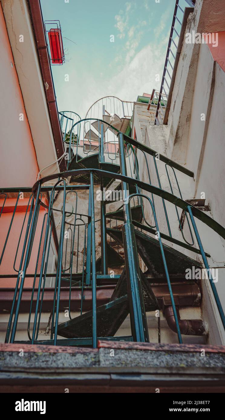 Scala a spirale tra due case colorate Foto Stock