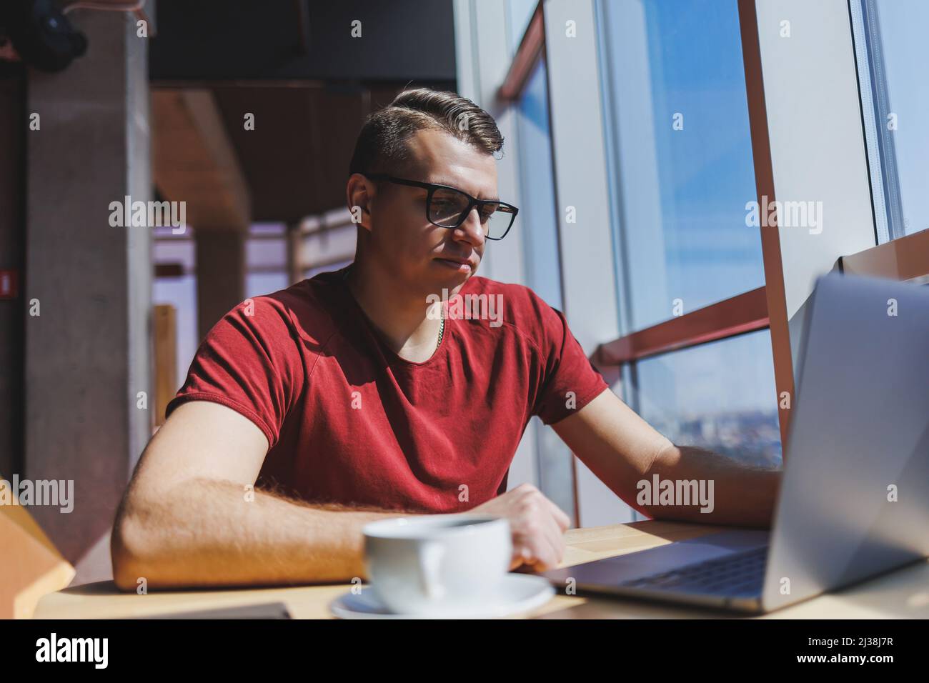 Sviluppatore di software intelligente seduto al desktop in uno spazio di collaborazione con il laptop e la creazione di un'idea di pubblicazione, utilizzando netbook per la messaggistica e il networking du Foto Stock