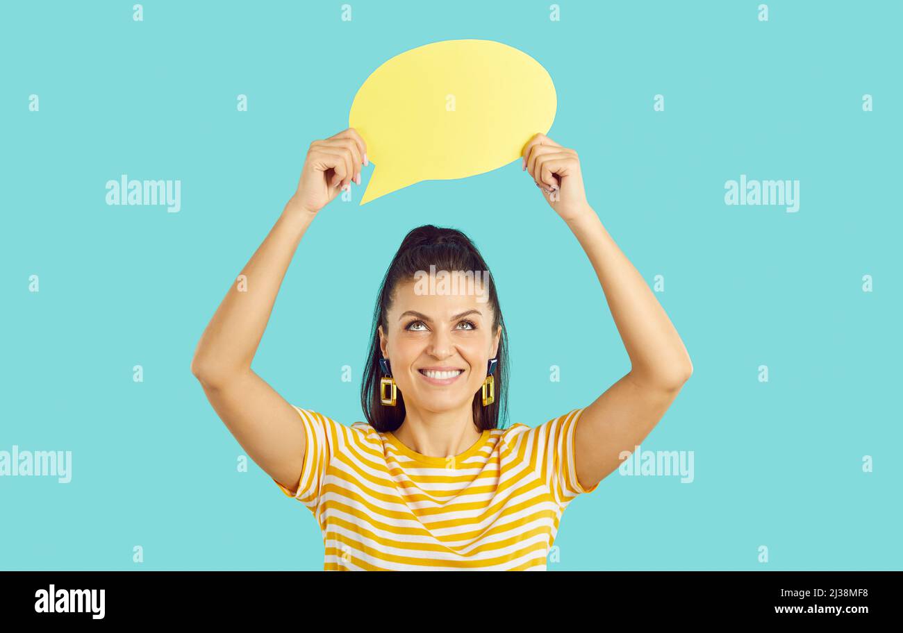 Felice giovane donna sorridente e tenendo vuoto palloncino di discorso giallo o bolla di pensiero Foto Stock