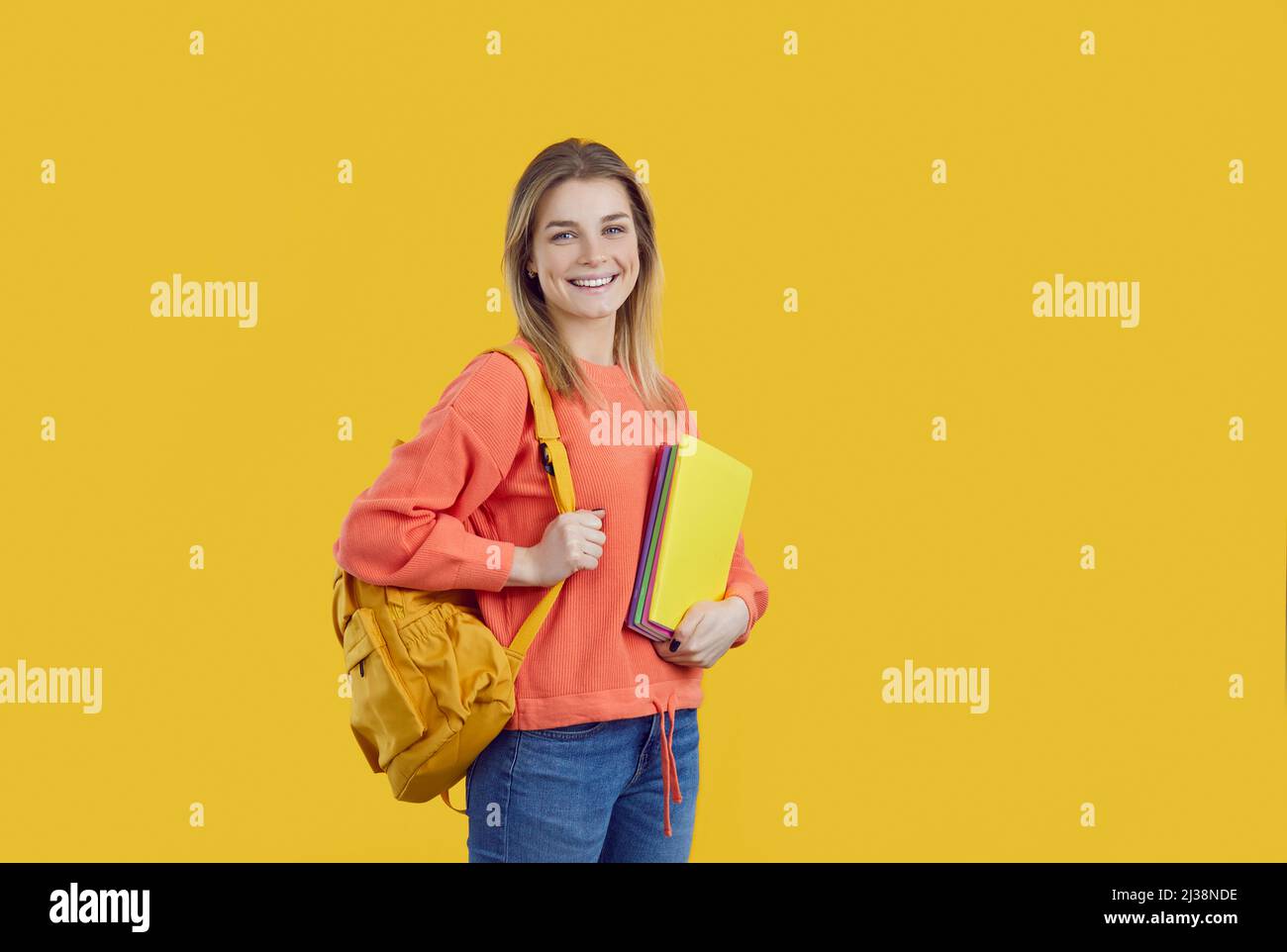 Felice studente universitario con zaino e notebook isolati su sfondo a colori Foto Stock