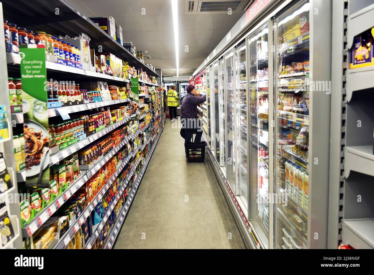 Supermarket Aisle con un membro del personale scaffalature Foto Stock