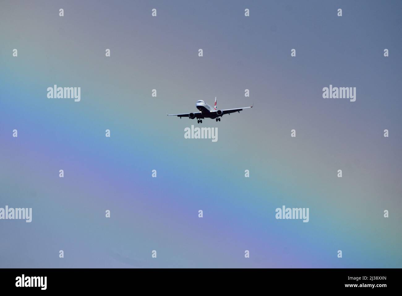Aereo che arriva per atterrare all'aeroporto di London City con un arcobaleno sullo sfondo Foto Stock