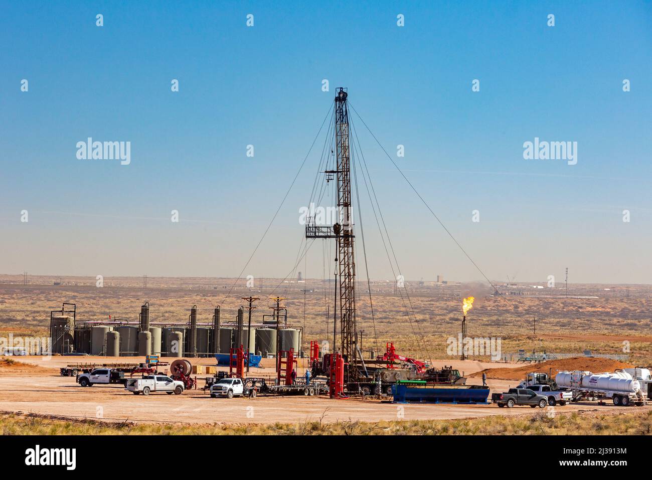 Loving, New Mexico - un carro di perforazione di petrolio e serbatoi di stoccaggio di petrolio nel bacino di Permian. Il bacino di Permian è una delle principali aree di produzione di petrolio e gas nella zona ovest di T. Foto Stock