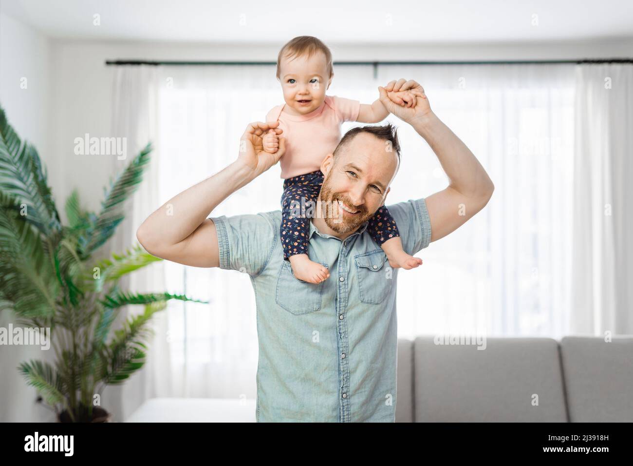 padre ha la figlia del bambino sulla spalla che ha divertente sul soggiorno Foto Stock