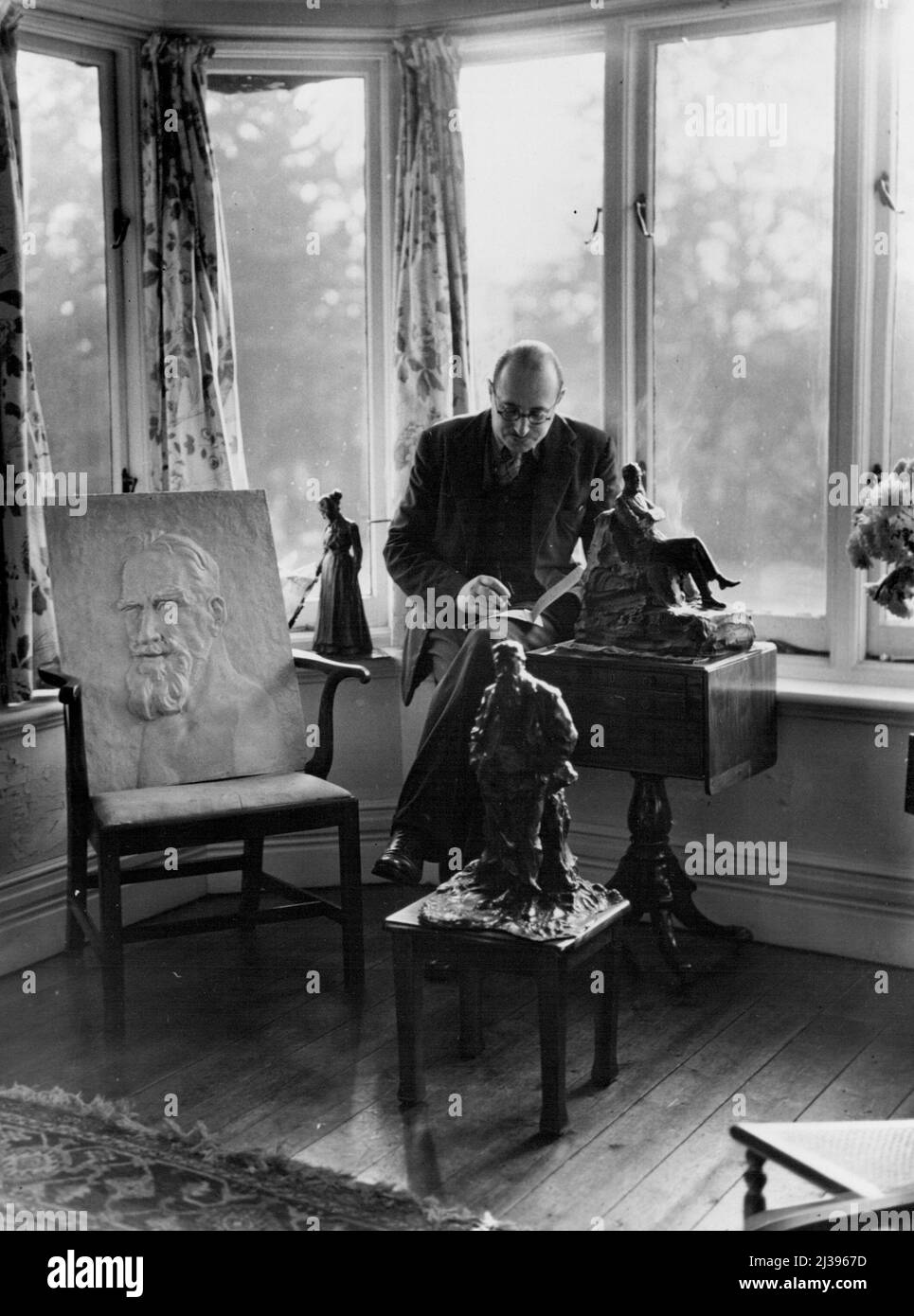 Shaw's Boswell - il dottor Loewenstein prende atto - quanto presto si formeranno come un autorevole 'vita di Shaw' paragonabile a 'Johnson' di Boswell? Si siede su un davanzale nel salotto di Shaws Corner; la sedia è occupata permanentemente da una placca di Shaw che è stata usata nella pubblicità del film per 'Caesar e Cleopatra'. La statuetta di Shaw è di Paul Troubetzkoy (1926), che è anche responsabile della figura di William Morris in primo piano. Luglio 18, 1947. (Foto di Pictorial Press). Foto Stock