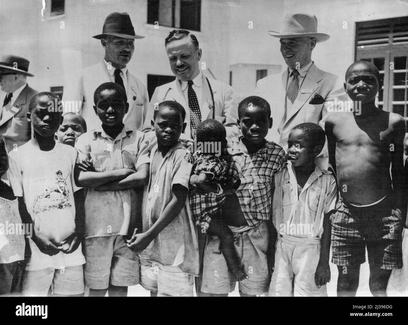 Tutti volevano essere nella foto -- i bambini africani scherzavano l'un l'altro per entrare nella foto, con l'eccezione del bambino, che era più interessato ai visitatori illustri quando un partito dei delegati parlamentari del Commonwealth visitò la tenuta di alloggiamento di Port Tudor a Mombasa, Kenya. I delegati sono - da sinistra a destra il Conte di Lucan, M.C. (membro laburista della Casa dei Lord): Il Sig. Donald (fiammingo del Canada); e il Sig. Arthur Henderson (membro laburista di Rowley Regis e Tipton). Settembre 07, 1954. Foto Stock