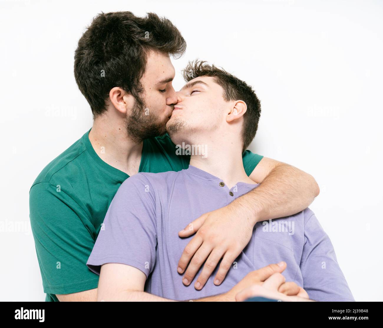 giovane-coppia-gay-in-piedi-insieme-su-sfondo-isolato-dando-bacio-2j39b48.jpg
