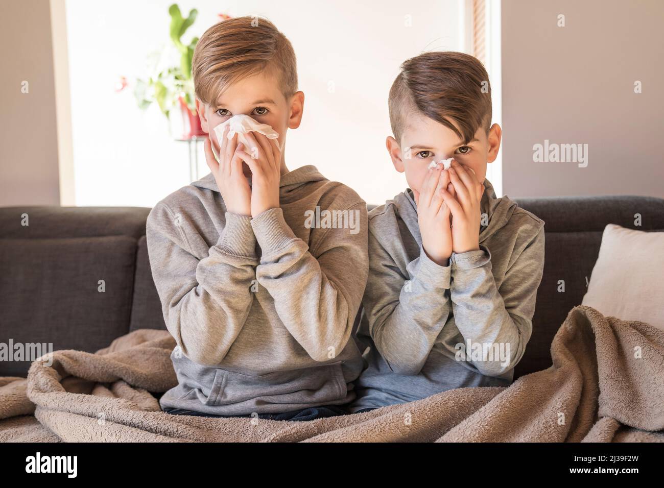 tosse i ragazzi dei piccoli fratelli a casa che hanno influenza sul divano Foto Stock