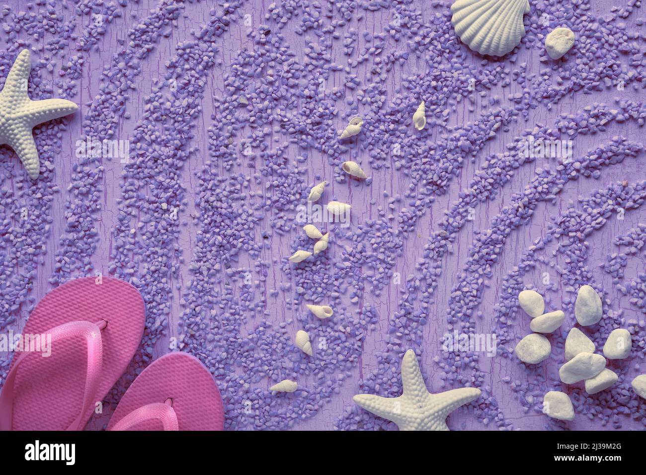 Estate al mare. Infradito in gomma magenta, pantofole su ciottoli con stelle marine, conchiglie e ciottoli, studio concept. Sfondo viola. Foto Stock