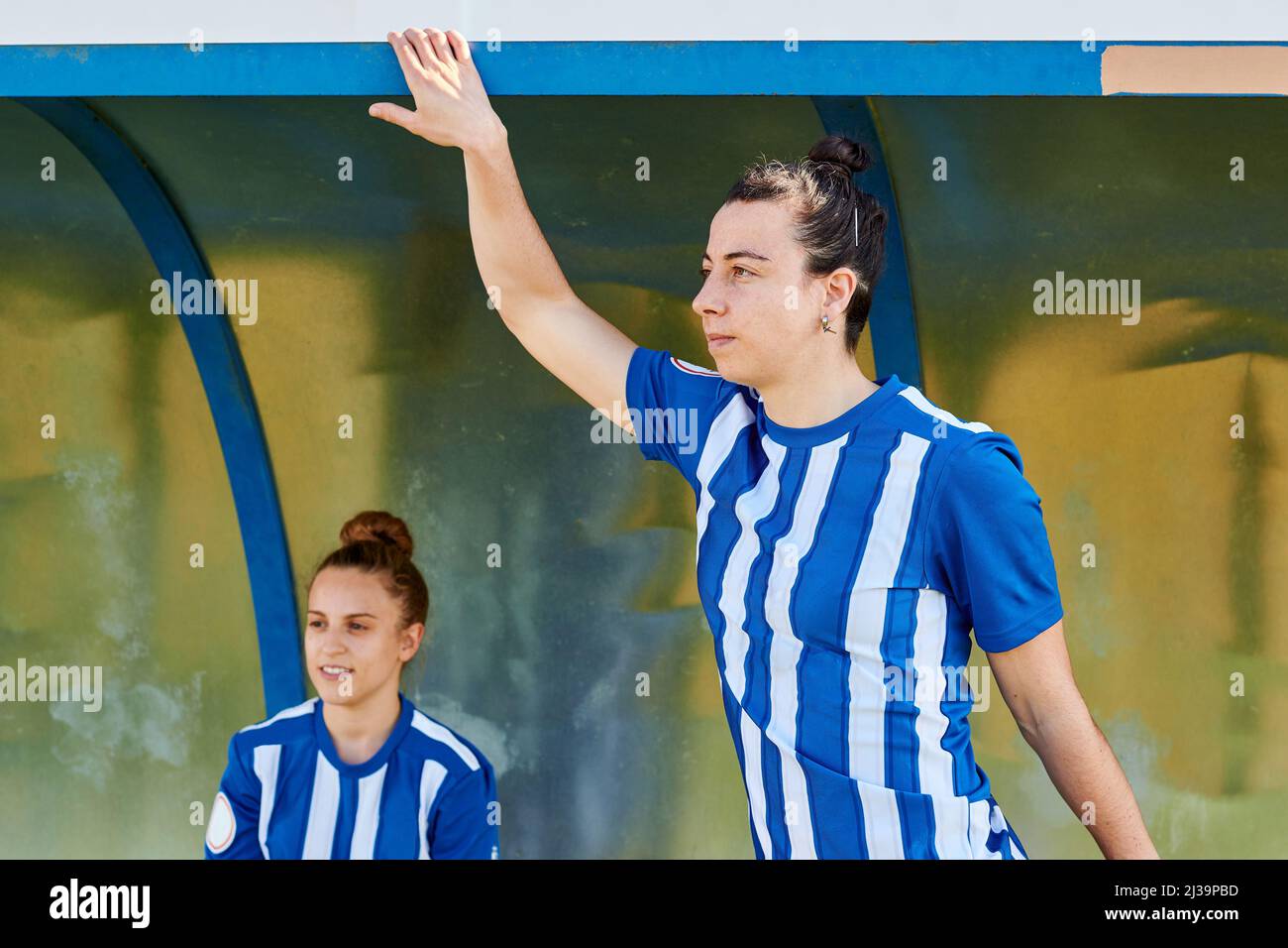Due giocatori di calcio donne guardano fuori sopra il campo di calcio dalla panchina Foto Stock