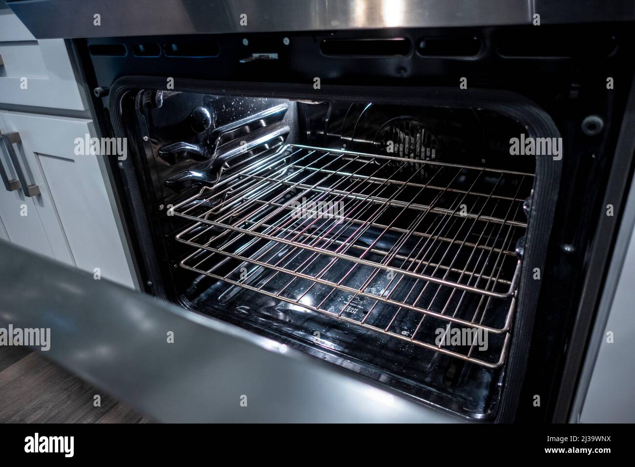 Vista ad angolo dell'interno di un forno pulito e nero, la porta leggermente aperta Foto Stock