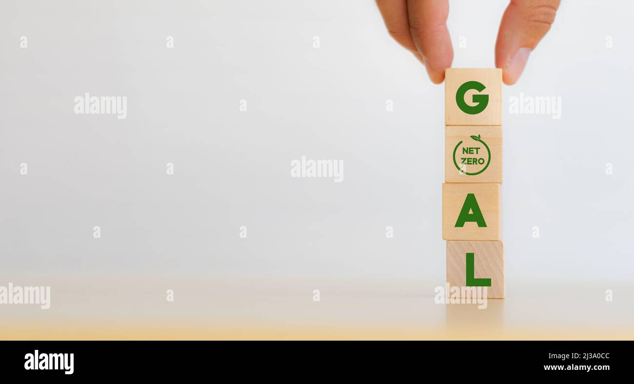 Obiettivo netto zero e concetto di strategia. Decarbonizzazione, economia a basse emissioni di carbonio per lo sviluppo sostenibile. Mettere a mano cubi verticali di legno con testo "OBIETTIVO" A. Foto Stock