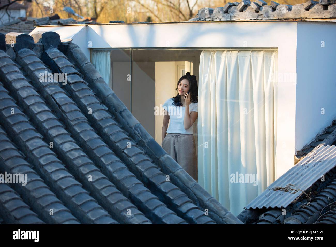 Giovane ragazza cinese che si gode il paesaggio architettonico tradizionale del siheyuan di Pechino in una finestra da pavimento a soffitto - foto di scorta Foto Stock