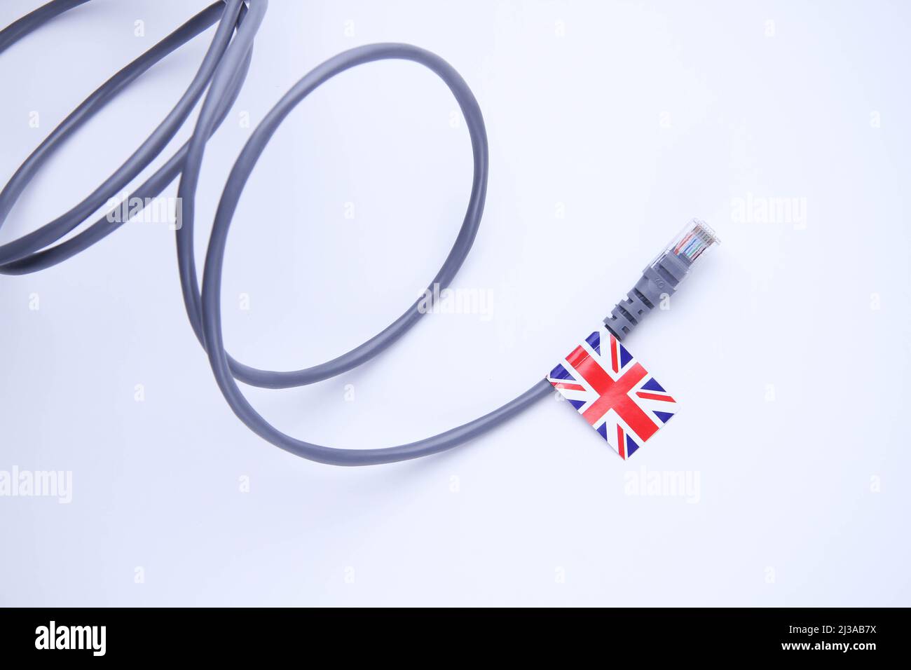 Cavo Internet con bandiera britannica. Connessione di un PC a Internet in Gran Bretagna. Primo piano del cavo multicore su sfondo bianco. Foto Stock
