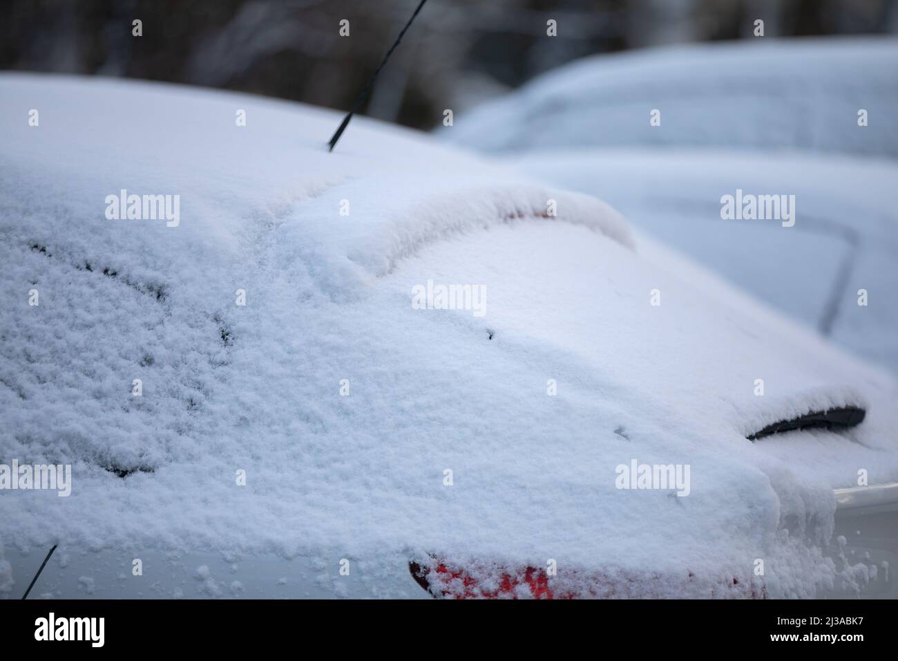 Un'auto coperta da un sottile strato di neve durante la stagione invernale. Foto Stock