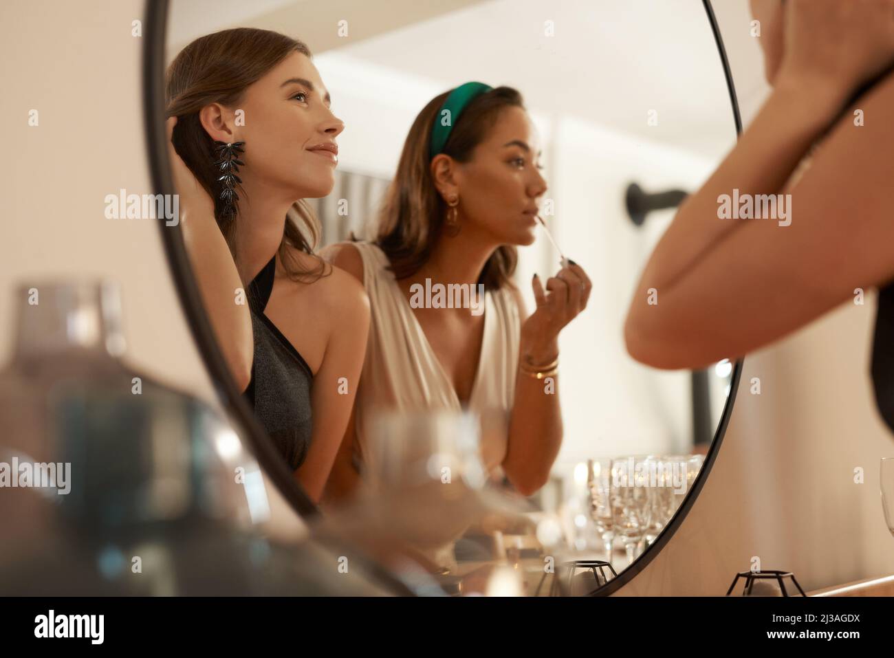 Ho avuto modo di mantenere intatta la bara. Scatto di due giovani amici in piedi insieme e utilizzando uno specchio per ritoccare il loro trucco durante una cena partito. Foto Stock