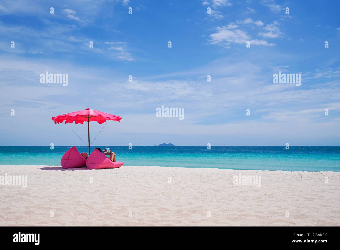 Ombrellone rosa e posto a sedere sulla spiaggia tropicale, sfondo vacanza., spiaggia idilliaca Foto Stock