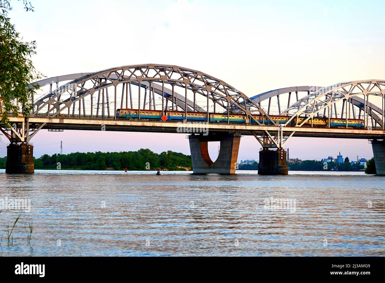 Ponte ferroviario attraverso il fiume con un treno passeggeri che lo attraversa Foto Stock