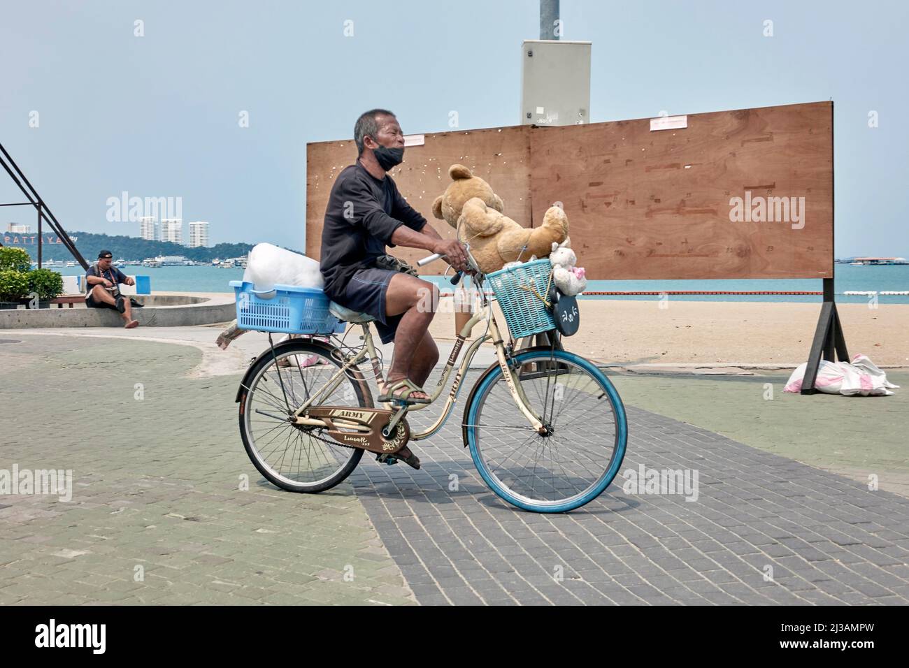 Uomo in bicicletta con grande orsacchiotto nel cesto Foto Stock