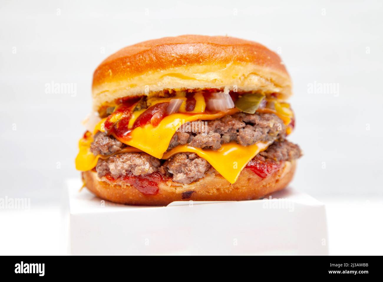 Hamburger a due piani con ciambelle di manzo e condimento su una scatola da asporto. Foto Stock
