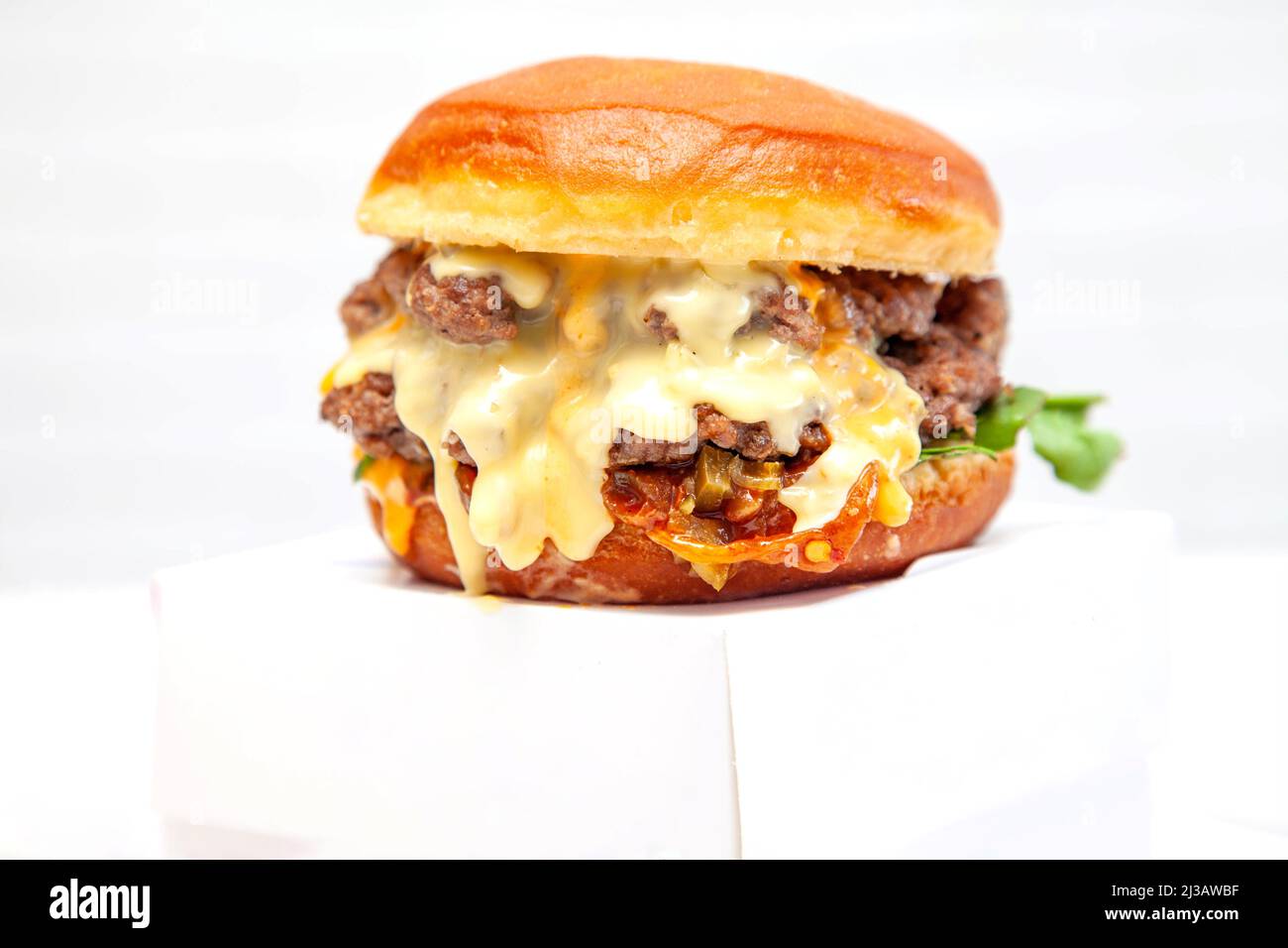 Hamburger a due piani con ciambelle di manzo e condimento su una scatola da asporto. Foto Stock