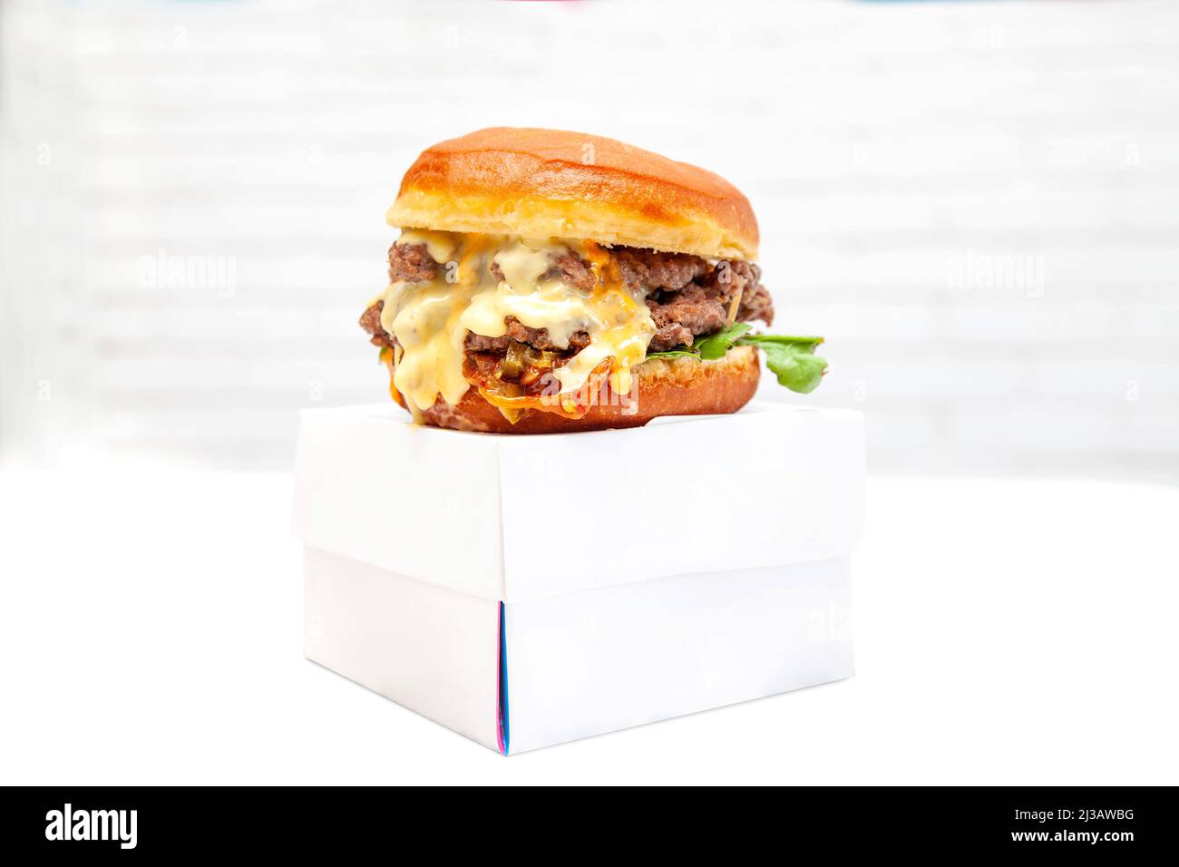 Hamburger a due piani con ciambelle di manzo e condimento su una scatola da asporto. Foto Stock