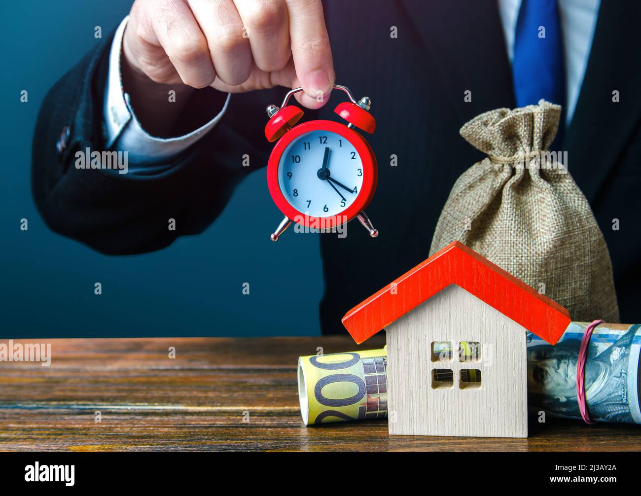 Realtor che tiene un orologio sopra la casa. Offerta limitata. Attività di noleggio. Offerte speciali per l'acquisto di una casa. Fare un mutuo ipotecario. Vendita stagionale. Inves Foto Stock