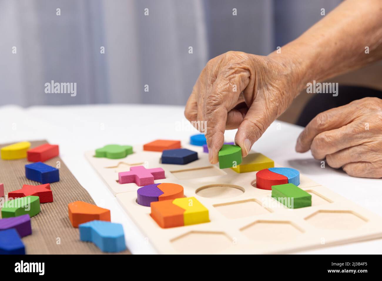 Caregiver e donna anziana giocare a forma di legno puzzle gioco per la prevenzione della demenza Foto Stock