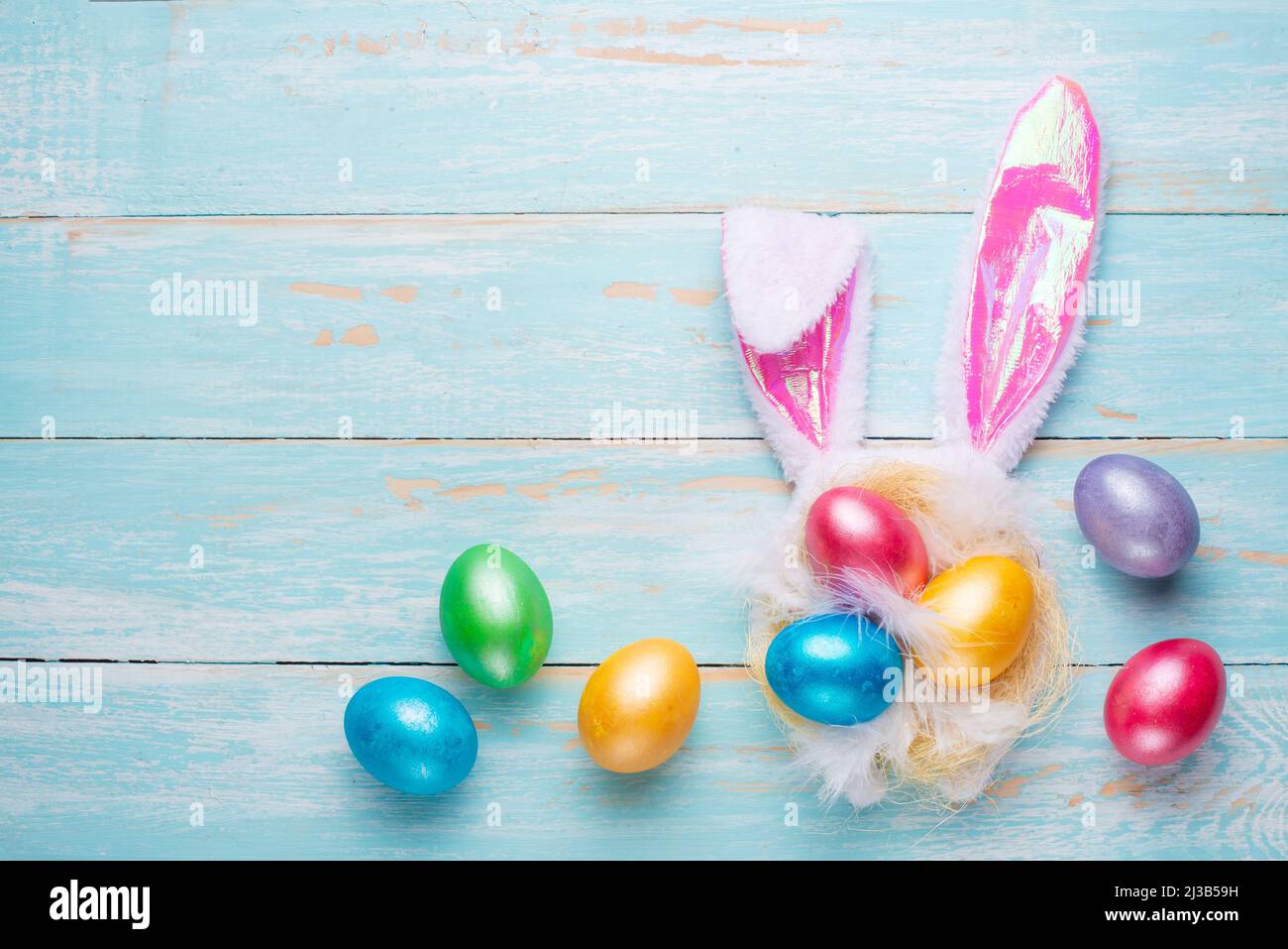 Uova di Pasqua multicolore e orecchie di coniglio. Disposizione piatta Foto Stock