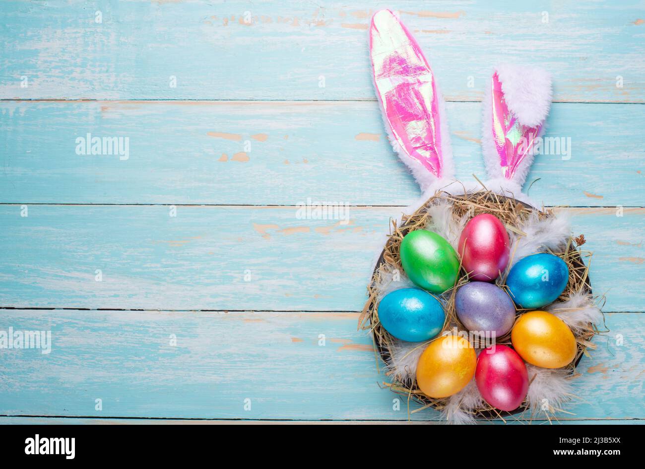 Uova di Pasqua multicolore e orecchie di coniglio. Disposizione piatta Foto Stock