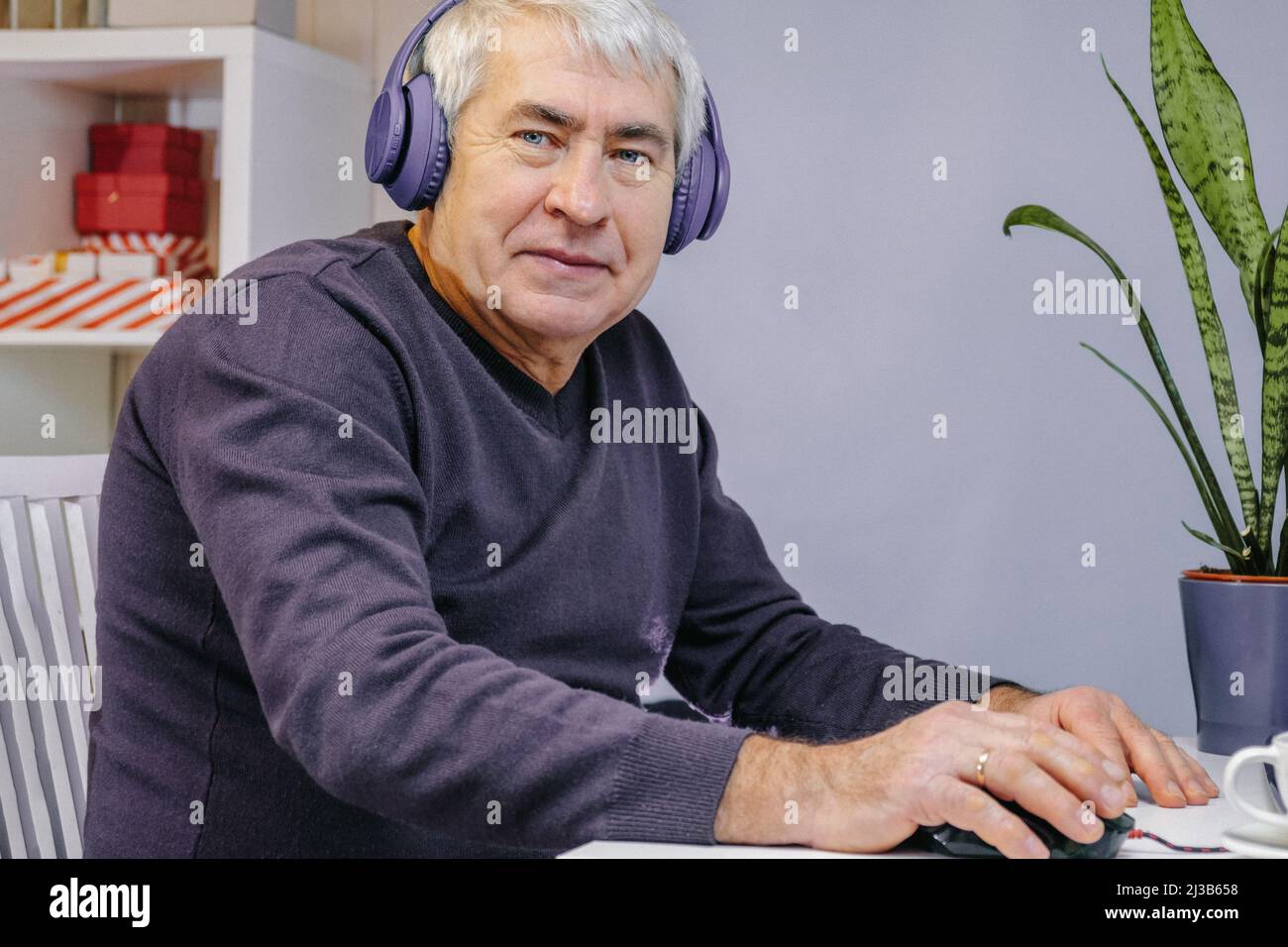 Uomo anziano felice che fa videochiamata al laptop. Old Man con cuffie collegate al computer portatile a casa. Tecnologia, persone, stile di vita e comunicazione Foto Stock