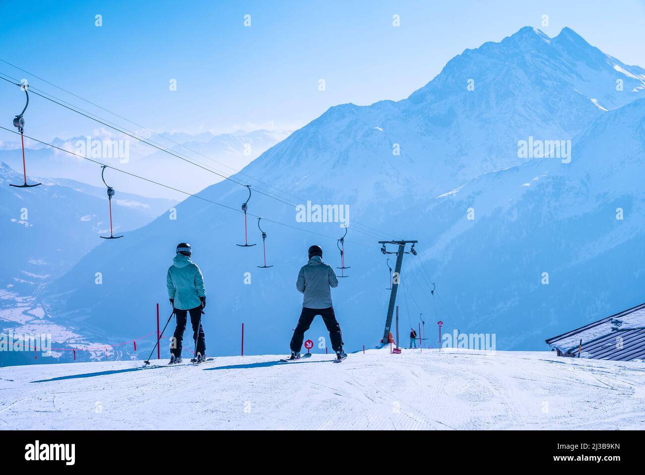 Sciatori che scivolano lungo la pista innevata in montagna nella località invernale Foto Stock