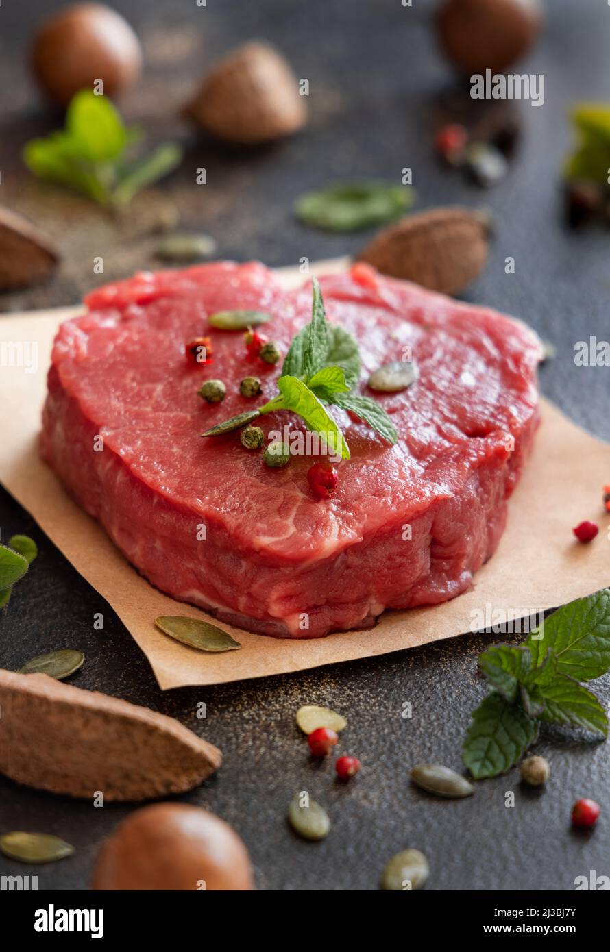 Bistecca di filetto di manzo crudo su un tavolo scuro da vicino con spazio copia. Filetto mignon con spezie ed erbe. Concetto di cibo estivo, mangiatori di carne. Foto Stock