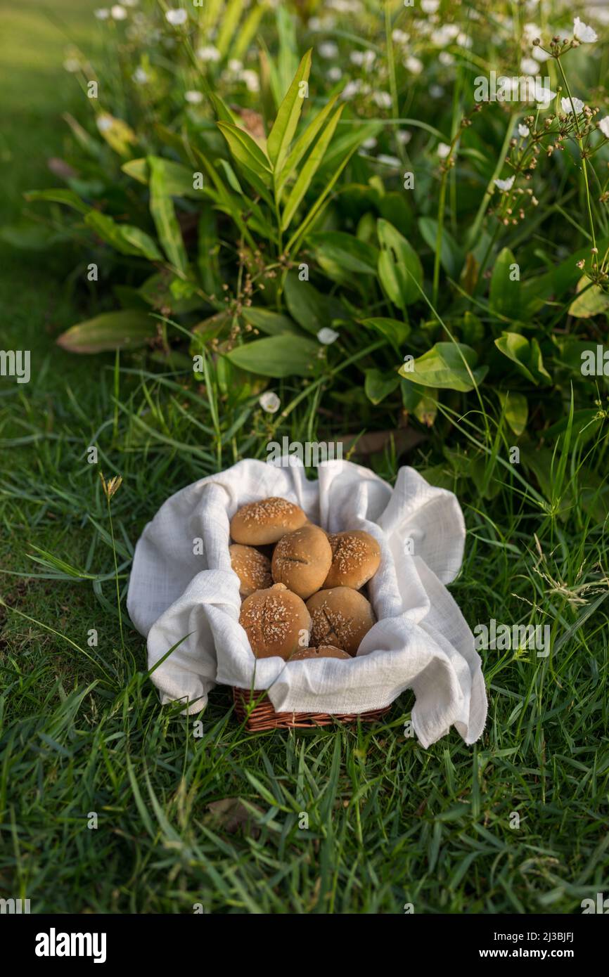 Composizione di ciambelle di farina bianca in cestello con tovagliolo bianco sull'erba verde. Foto di alta qualità Foto Stock