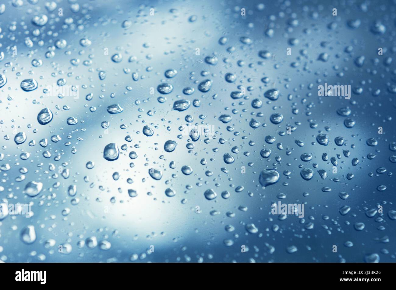Gocce d'acqua reali su sfondo blu gradazione, primo piano. Gocce di pioggia sul vetro della finestra. Condensa Foto Stock