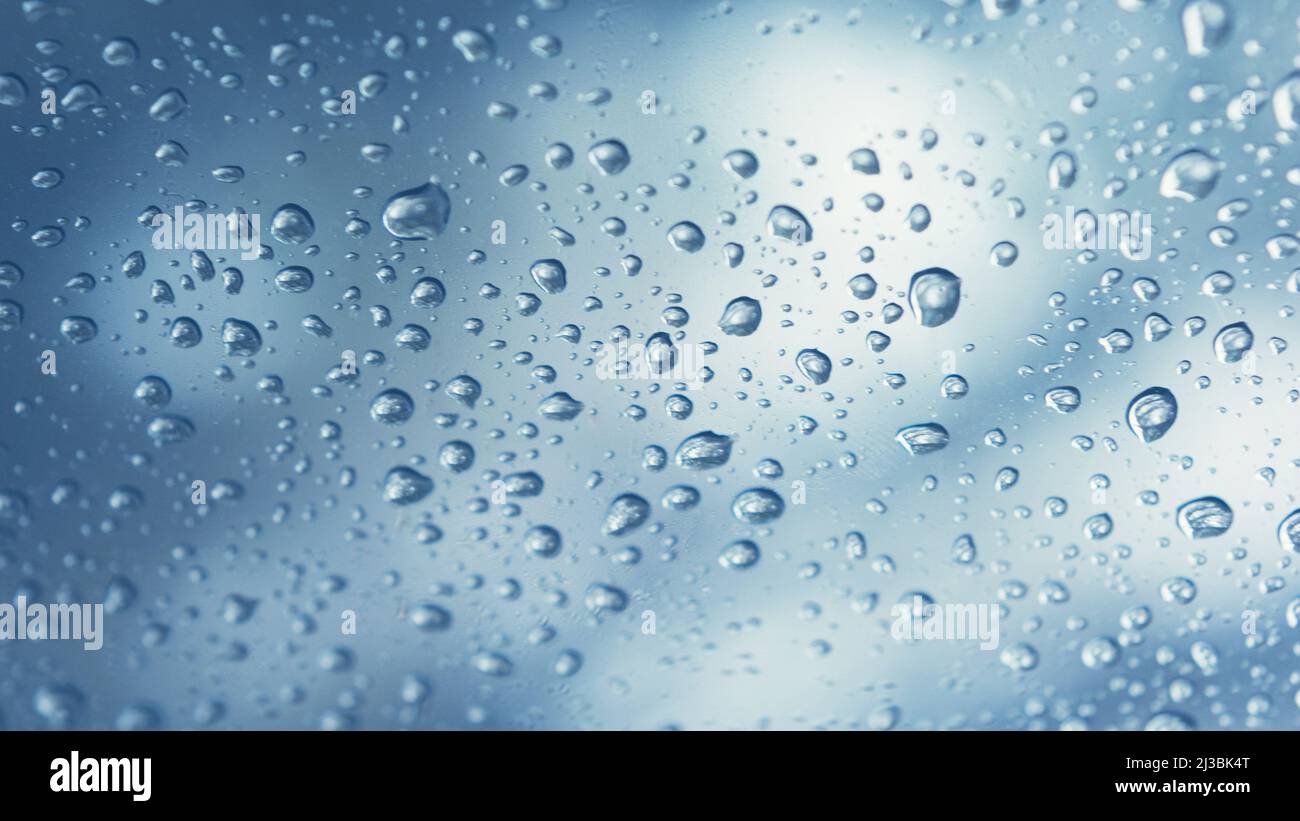 Gocce d'acqua reali su sfondo blu gradazione, primo piano. Gocce di pioggia sul vetro della finestra. Condensa Foto Stock