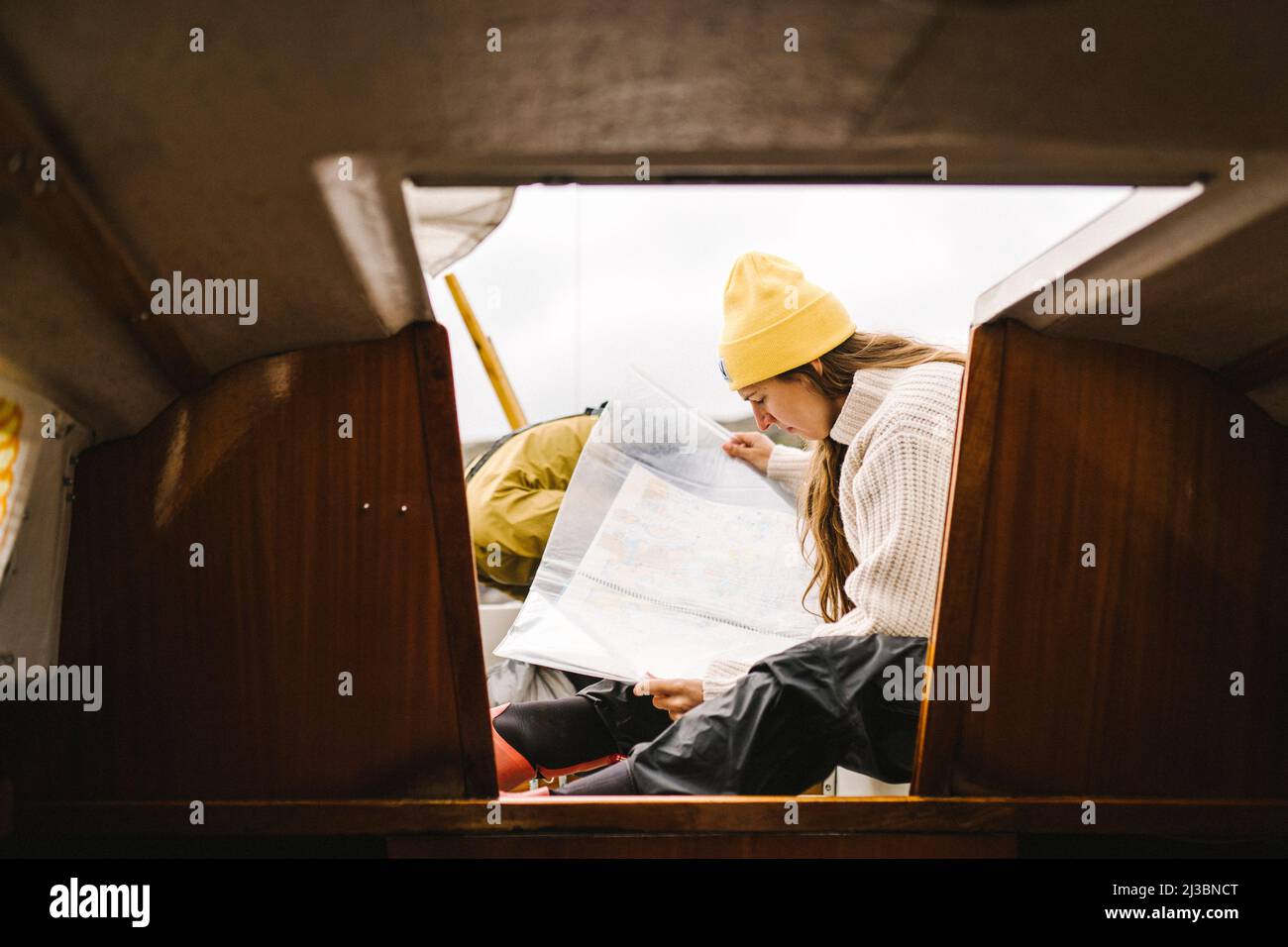 Donna che guarda la mappa all'ingresso della cabina della barca Foto Stock