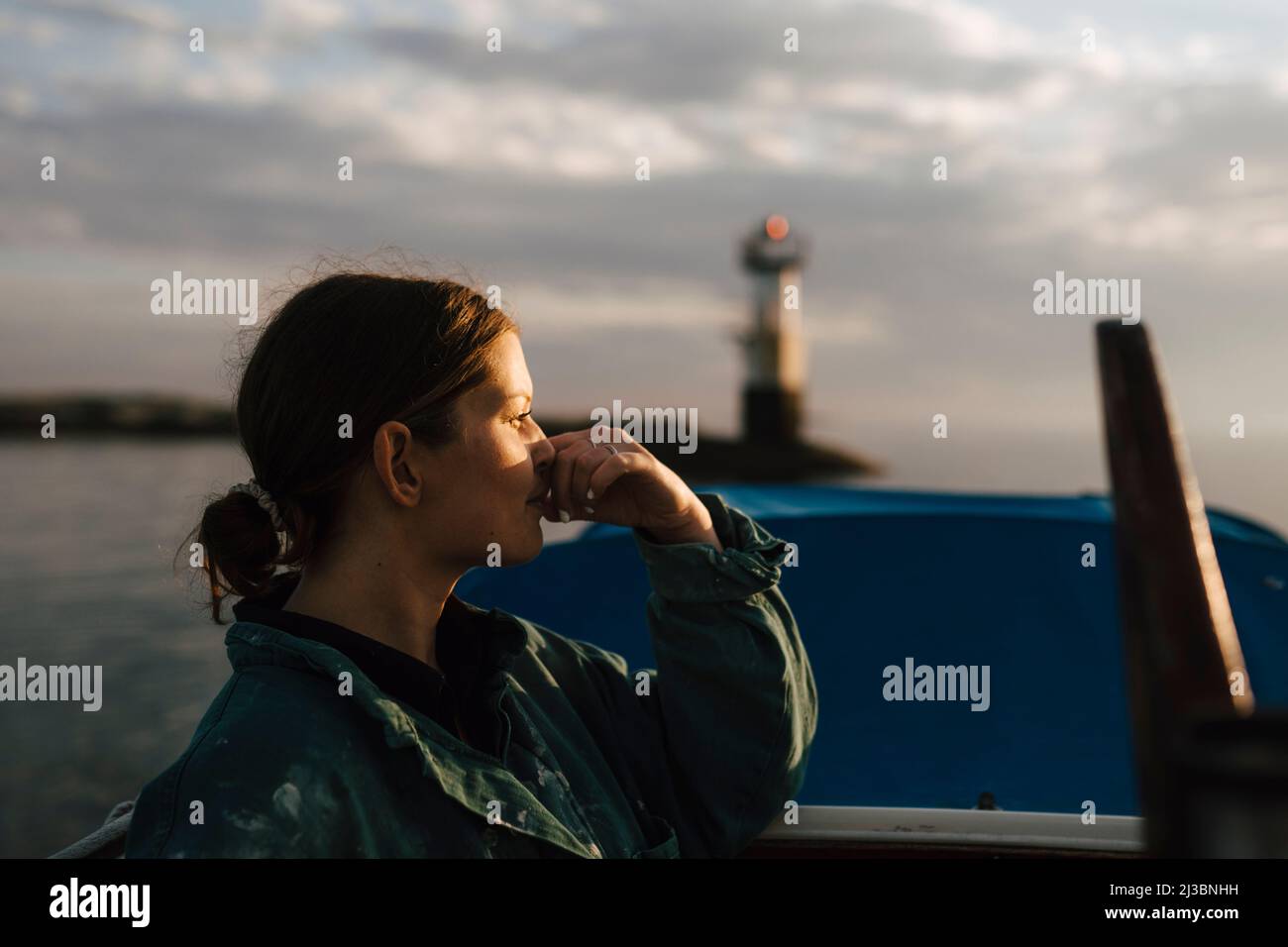 Giovane donna che guarda il mare al tramonto Foto Stock