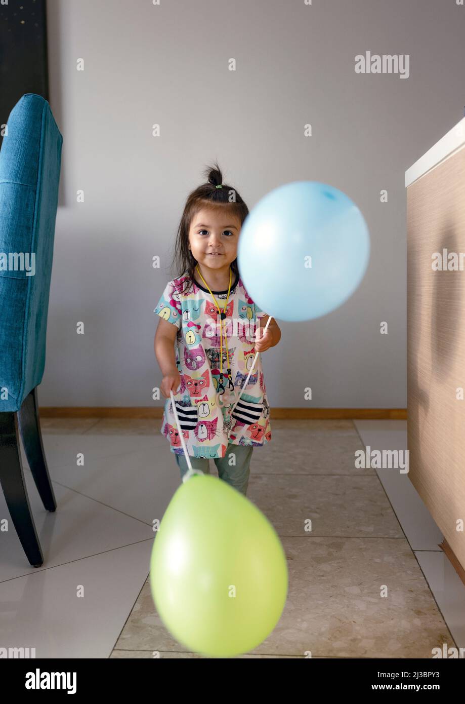 Ritratto di ragazza che tiene palloncini a casa Foto Stock