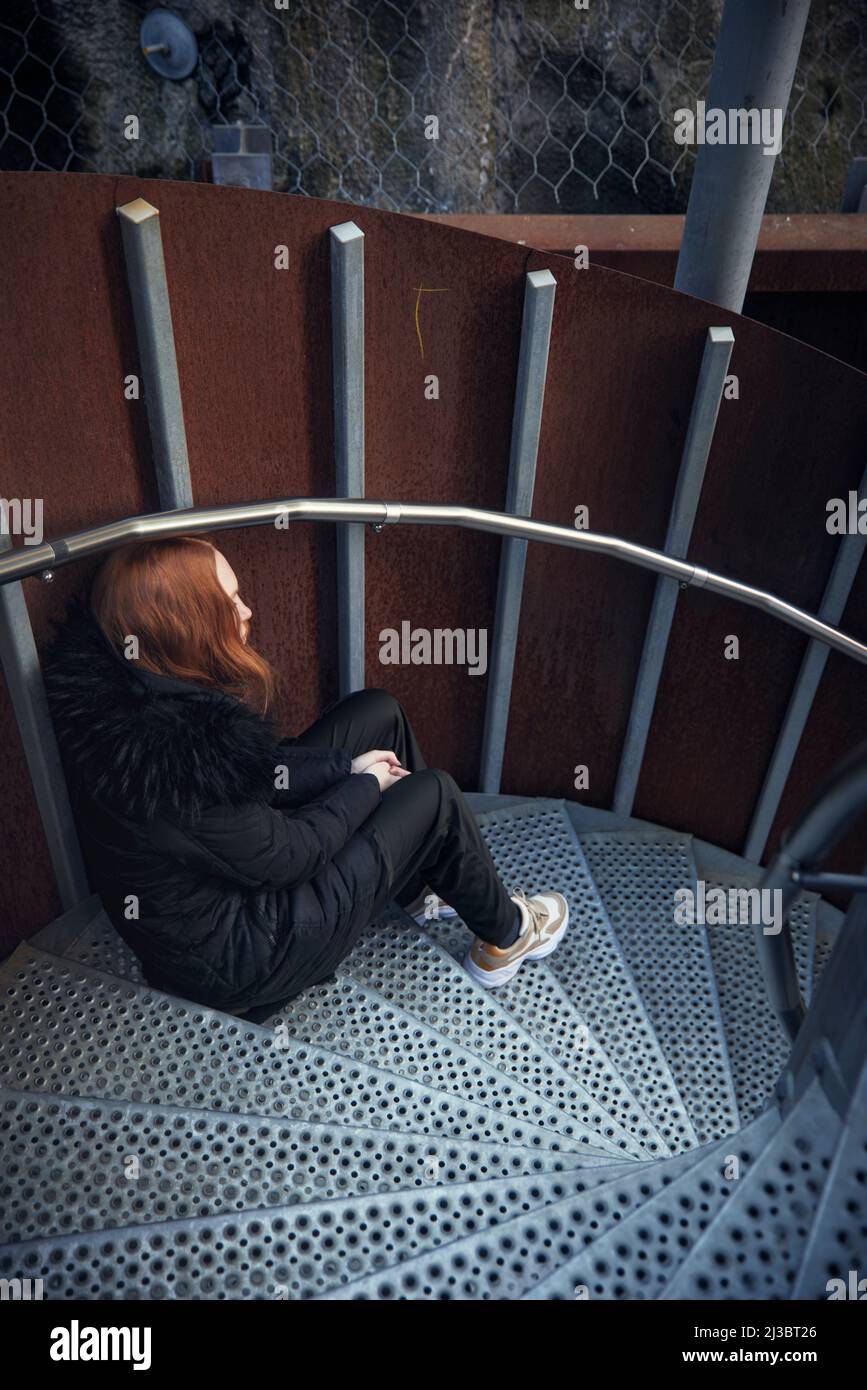 Giovane donna seduta sulle scale Foto Stock