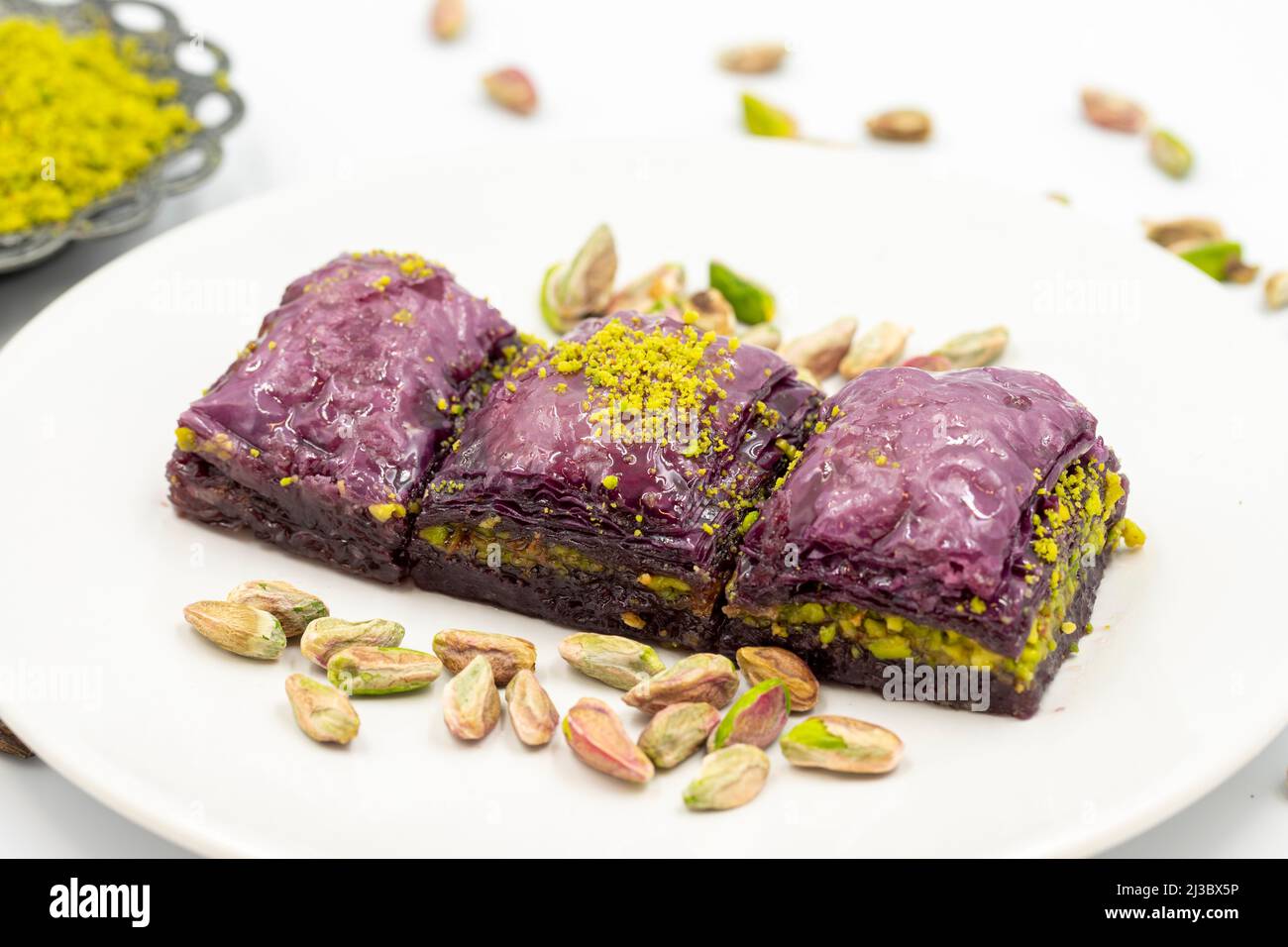 Pistacchio baklava viola su sfondo bianco. Baklava appositamente preparato per i diabetici. Specialità della cucina mediterranea tradizionale. Primo piano Foto Stock